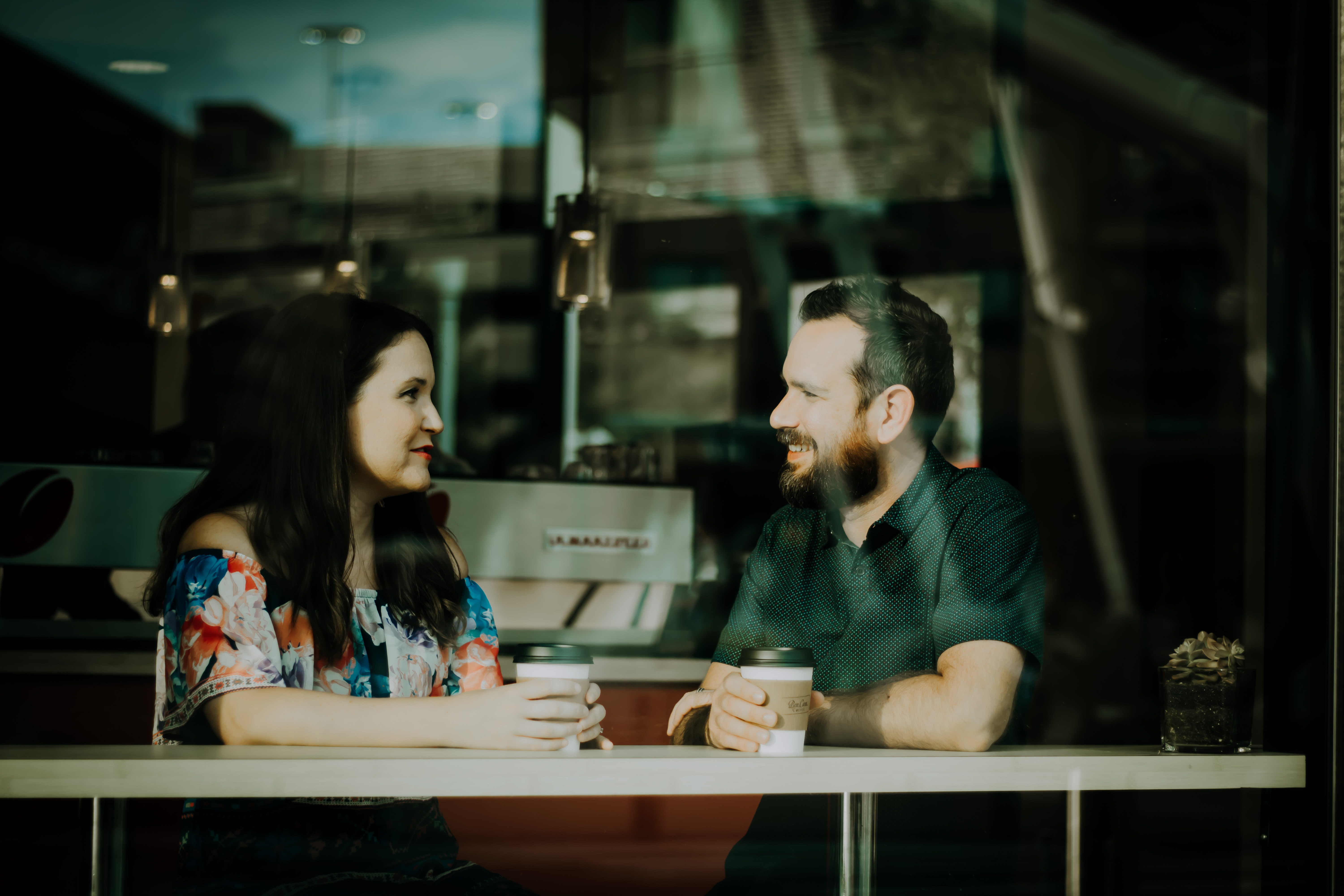 A woman and man sitting in the coffed shop bar having a conversation 